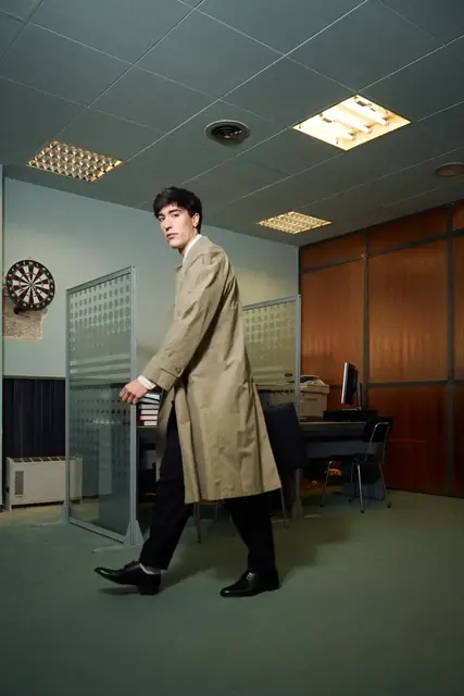 Modelo con gabardina cruzando una oficina, campaña de Dho