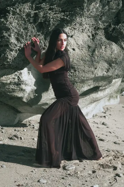 Modelo con vestido negro en una cueva junto al mar, sesión editorial