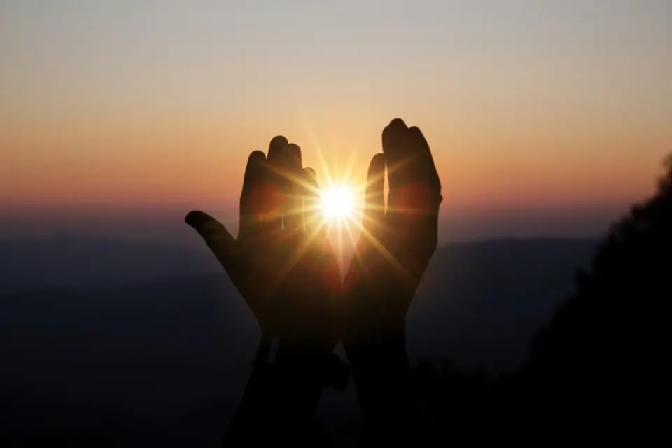 Manos al atardecer sosteniendo el sol